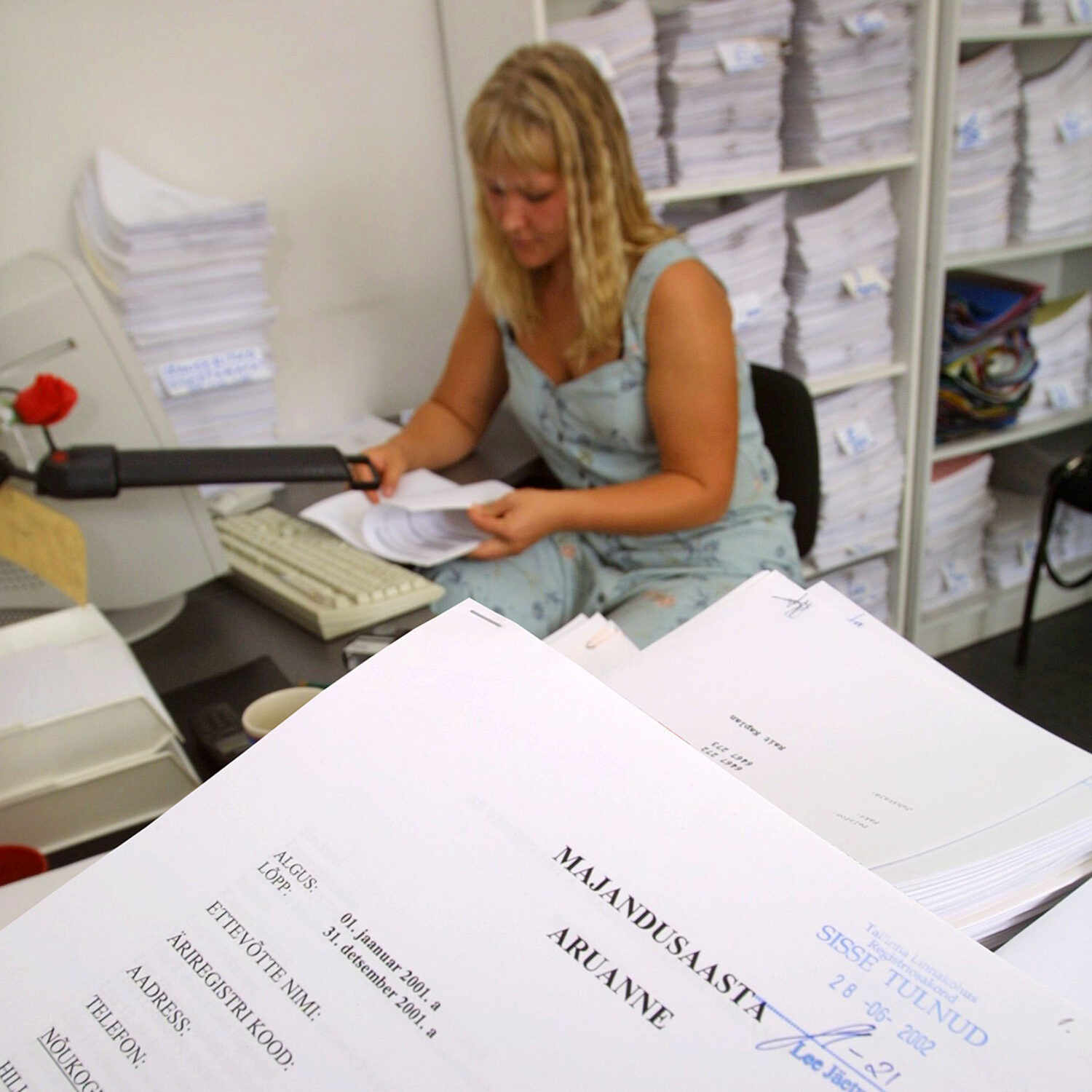 tehniline sekretär sisestamas astaaruandeid arvutisse.taamal kapp täis aruandeid, mis ootavad töötlemist